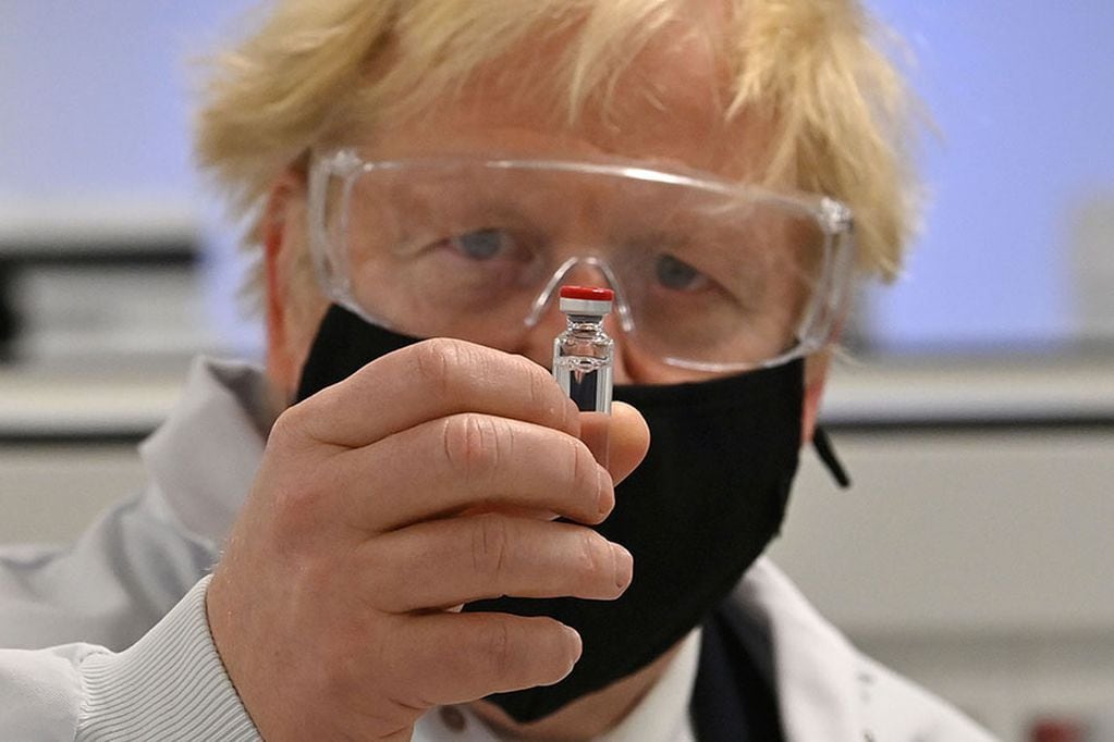 Britain's Prime Minister Boris Johnson poses for a photograph with a vial of the AstraZeneca/Oxford University COVID-19 candidate vaccine, known as AZD1222, at Wockhardt's pharmaceutical manufacturing facility in Wrexham, north Wales, on November 30, 2...