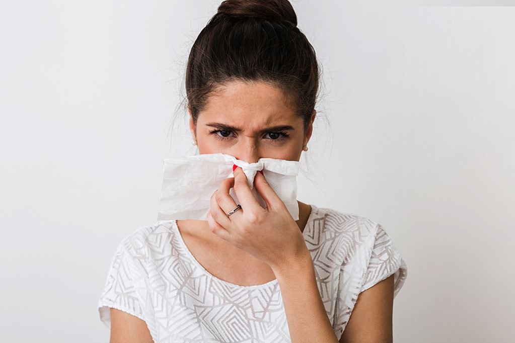close-up portrait of pretty woman blowing her nose with napkin, catch a cold, feeling sick, isolated, white studio background, frowning