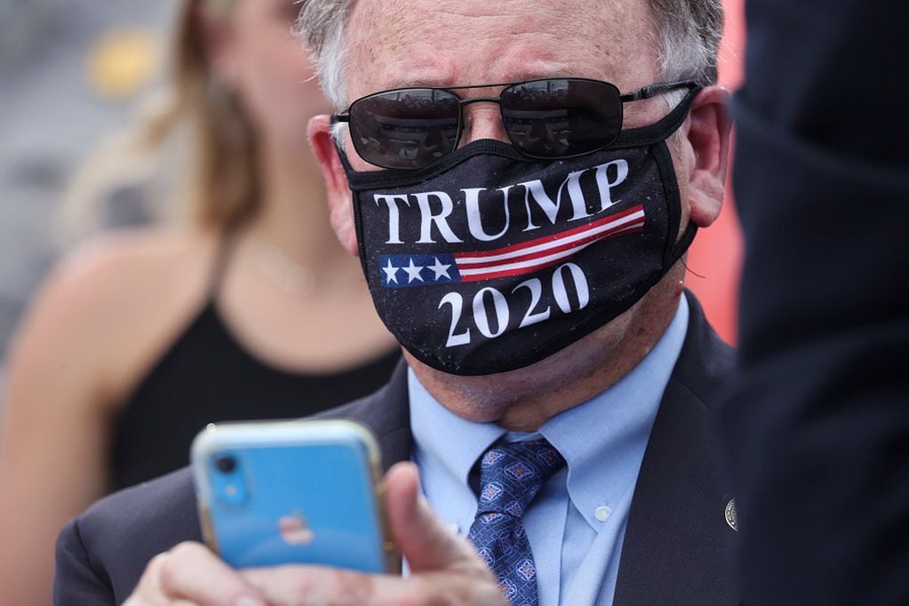 A supporter of U.S. President Donald Trump wearing a Trump 2020 protective face mask because of the coronavirus disease (COVID-19) outbreak listens as the president speaks about the state of Florida during a campaign stop at Jupiter Inlet Lighthouse and Museum in Jupiter, Florida, U.S., September 8, 2020. REUTERS/Jonathan Ernst