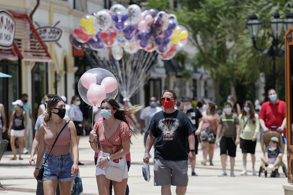 FILE - In this June 16, 2020, file photo, guests required to wear masks because of the coronavirus stroll through the Disney Springs shopping, dining and entertainment complex in Lake Buena Vista, Fla. Magic Kingdom and Animal Kingdom will reopen on July 11. In May, the company opened Disney Springs. (AP Photo/John Raoux, File)