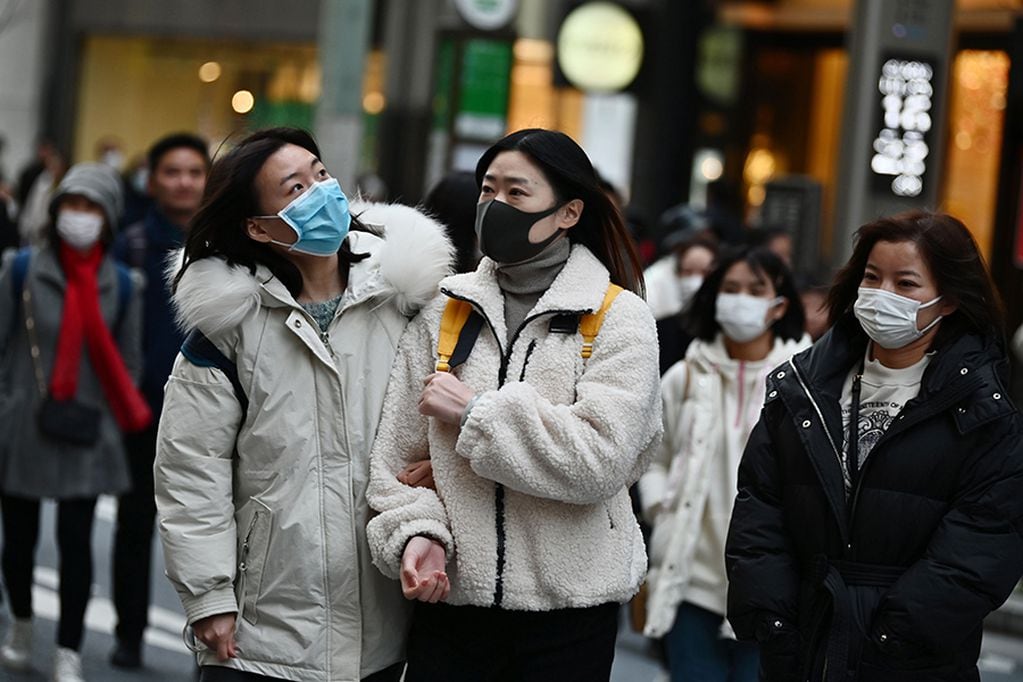 Pedestrians wearing protective masks to help stop the spread of a deadly virus which began in the Chinese city of Wuhan, walk on a street in Tokyo's Ginza area on January 25, 2020. - Japan's health authorities on January 25 confirmed the country's third case of the coronavirus which emerged in the Chinese city of Wuhan. (Photo by CHARLY TRIBALLEAU / AFP)