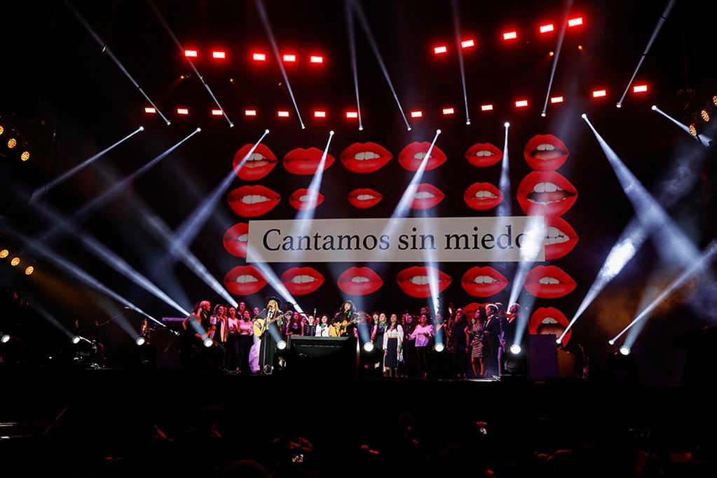 Chilean singer Mon Laferte, center, is joined on stage by Mexico's Vivir Quintana, center left, and a chorus of dozens to perform an anti-femicide song titled "Song without fear," during a concert by female performers on the eve of International Women's Day, in the Zocalo in Mexico City, Saturday, March 7, 2020. Protests against gender violence in Mexico have intensified in recent years amid an increase in killings of women and girls, and women are expected to express their outrage in a march in Mexico City on Sunday. (AP Photo/Rebecca Blackwell)