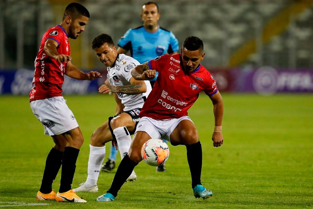 Chile's Colo Colo Peruvian midfielder Basilio Costa vies for the ball with Bolivia's Jorge Wilstermann midfielder Carlos Melgar (L) and forward, Argentine Esteban Orfano during their closed-door Copa Libertadores group phase football match at the Monumental Stadium in Santiago, on October 20, 2020, amid the COVID-19 novel coronavirus pandemic. (Photo by Alberto Valdes / POOL / AFP)