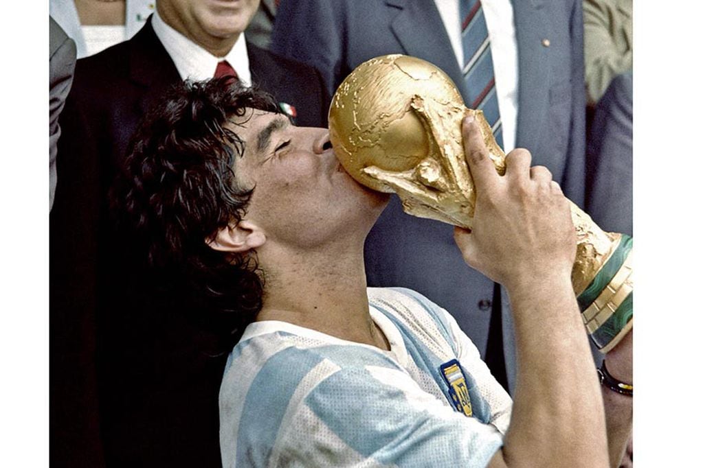 (FILES) In this file photo taken on June 29, 1986 Argentina's football star team captain Diego Maradona kisses the World Soccer Cup won by his team after a 3-2 victory over West Germany on at the Azteca stadium in Mexico City. - Argentine football legend Diego Maradona will be buried on November 26, 2020 on the outskirts of Buenos Aires, a spokesman said. Maradona, who died of a heart attack Wednesday at the age of 60, will be laid to rest in the Jardin de Paz cemetery, where his parents were also buried, Sebastian Sanchi told AFP. (Photo by - / AFP)