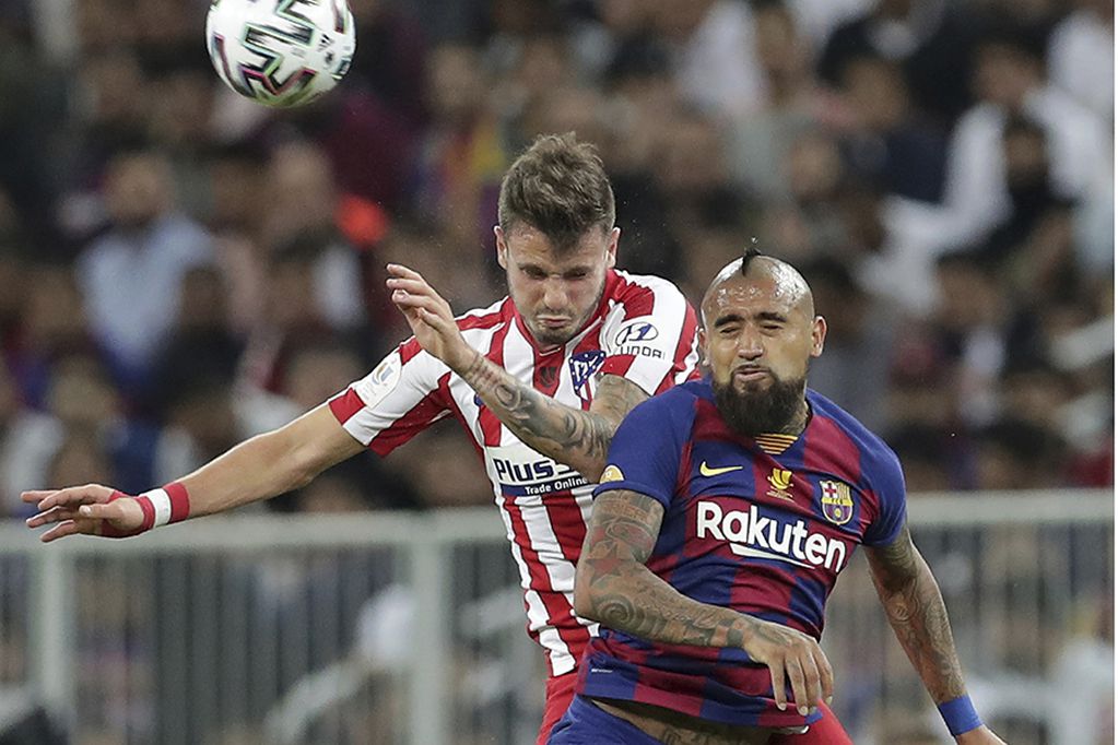 Barcelona's Arturo Vidal, right, jumps for the ball with Atletico Madrid's Saul during the Spanish Super Cup semifinal soccer match between Barcelona and Atletico Madrid at King Abdullah stadium in Jiddah, Saudi Arabia, Thursday, Jan. 9, 2020. (AP Photo/Hassan Ammar)