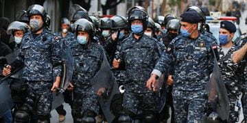Lebanese police wear face masks as they walk together, during a protest against the collapsing Lebanese pound currency near Lebanon's Central Bank in Beirut