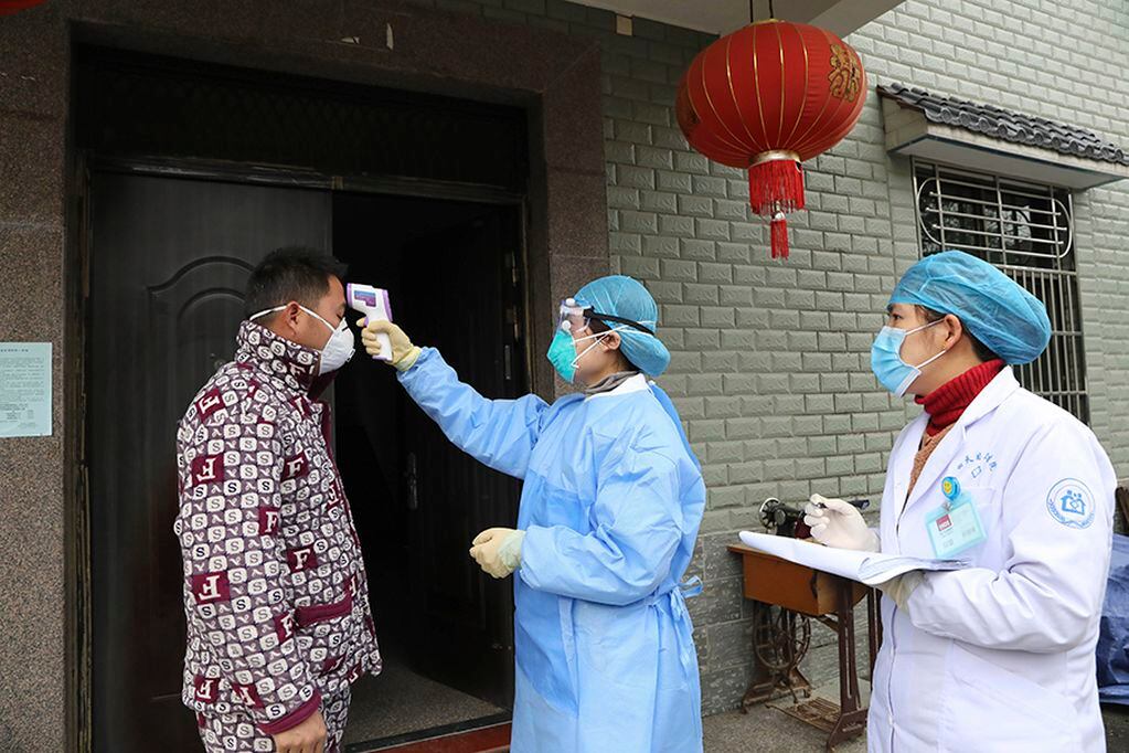 FILE - In this Jan. 27, 2020 photo, community health workers check the temperature of a person who recently returned from Hubei Province, center of a virus outbreak, in Hangzhou in eastern China's Zhejiang Province.  As China institutes the largest quarantine in human history, locking down more than 50 million people in the center of the country, those who have recently been to Wuhan are being tracked, monitored, turned away from hotels and shoved into isolation at their homes and in makeshift quarantine facilities.  (Chinatopix via AP)