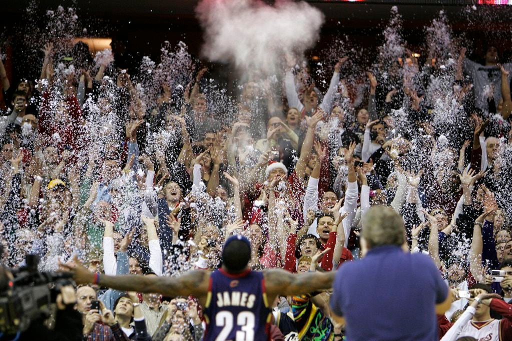 FILE - In this Dec. 25, 2008, file photo, fans toss confetti to mimic Cleveland Cavaliers' LeBron James's pre-game chalk toss before an NBA basketball game against the Washington Wizards in Cleveland. Billions has been spent on state-of-the-art sports facilities over the last quarter-century, but there is no way to prevent the potential spread of a virus through coughing or sneezing. Officials are working on safety protocols and looking at new technology in hopes of making stadiums and arenas as safe as they can. (AP Photo/Mark Duncan, File)