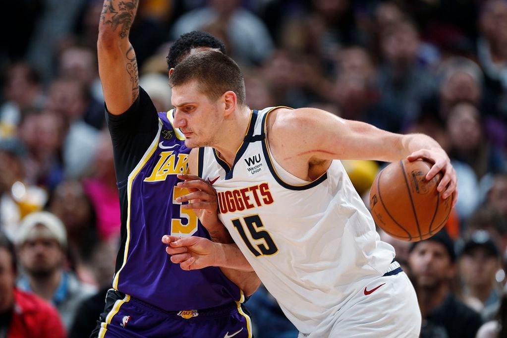 FILE - In this Feb. 12, 2020, file photo, Denver Nuggets center Nikola Jokic drives as Los Angeles Lakers forward Anthony Davis defends during the first half of an NBA basketball game in Denver. A person with knowledge of the situation says Jokic has tested positive for the coronavirus and is quarantining in his native Serbia. (AP Photo/David Zalubowski, File)