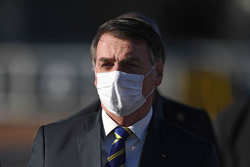 (FILES) In this file photo taken on May 12, 2020, Brazilian President Jair Bolsonaro wears a face mask as he arrives at the flag-raising ceremony before a ministerial meeting at the Alvorada Palace in Brasilia, Brazil, amid the new coronavirus pandemic. - As the number of dead from coronavirus shot up in Brazil, the popularity of far right President Jair Bolosonaro has remained unchanged. (Photo by EVARISTO SA / AFP)
