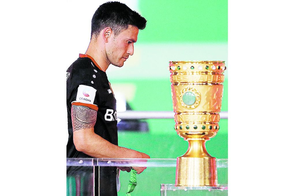Leverkusen's Chilean midfielder Charles Mariano Aranguiz walks past the German Cup (DFB Pokal) trophy after the final football match Bayer 04 Leverkusen v FC Bayern Munich at the Olympic Stadium in Berlin on July 4, 2020. (Photo by Michael Sohn / POOL / AFP) / DFB REGULATIONS PROHIBIT ANY USE OF PHOTOGRAPHS AS IMAGE SEQUENCES AND QUASI-VIDEO.