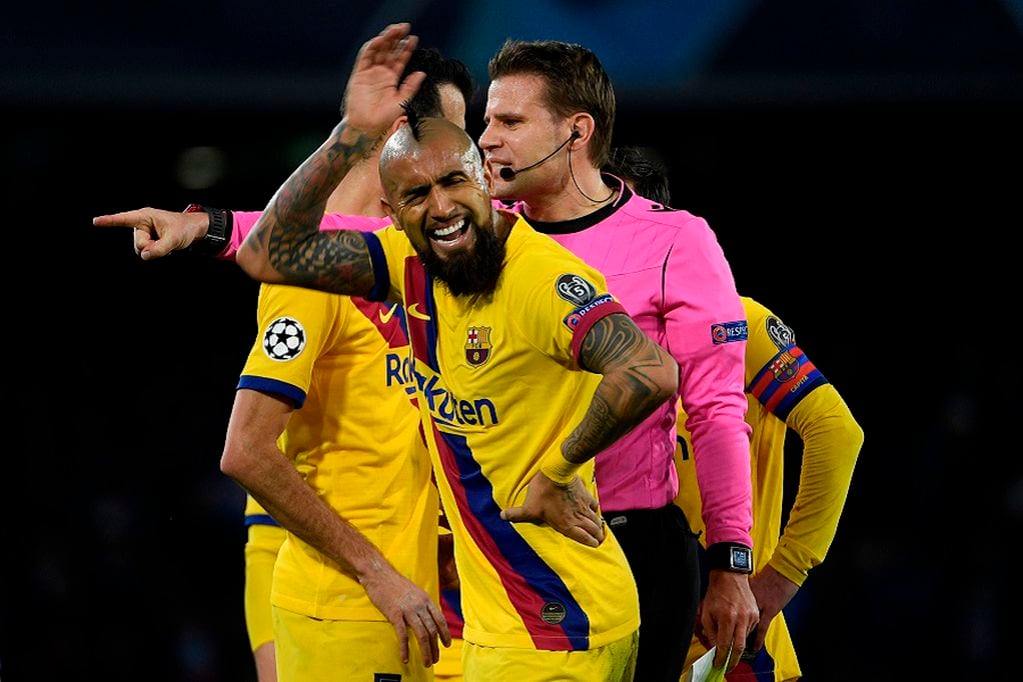 Barcelona's Chilean midfielder Arturo Vidal (L) reacts as he receives a yellow card from German referee Felix Brych (R)  during the UEFA Champions League round of 16 first-leg football match between SSC Napoli and FC Barcelona at the San Paolo Stadium in Naples on February 25, 2020. (Photo by Filippo MONTEFORTE / AFP)