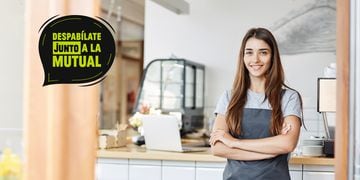 Young lady entrepreneur running a successful small cafe. Standing in front of coffee machine with arms crossed.