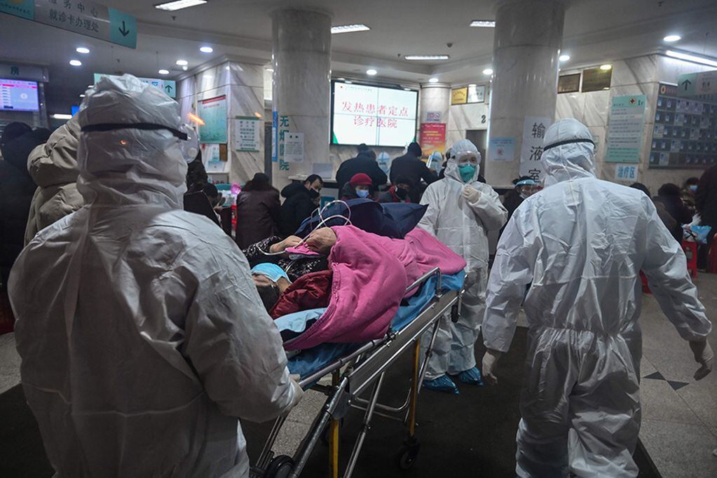 TOPSHOT - In this photo taken on January 25, 2020, medical staff wearing protective clothing to protect against a previously unknown coronavirus arrive with a patient at the Wuhan Red Cross Hospital in Wuhan. - The number of confirmed deaths from a viral outbreak in China has risen to 54, with authorities in hard-hit Hubei province on January 26 reporting 13 more fatalities and 323 new cases. (Photo by Hector RETAMAL / AFP)