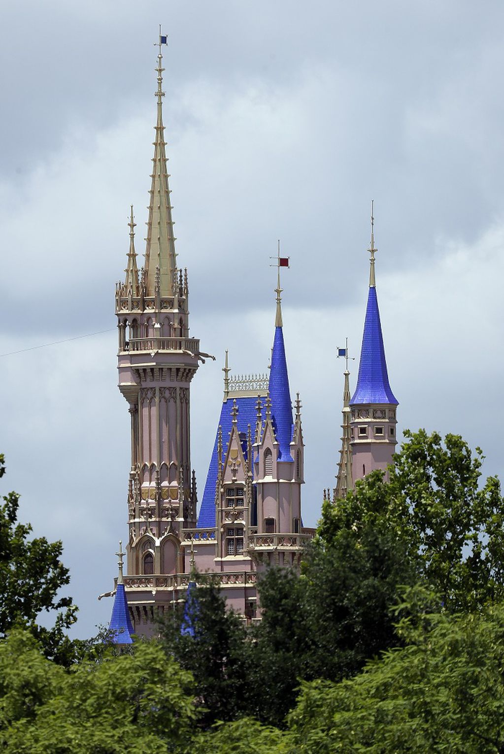 This photo shows the top of the newly painted Cinderella Castle in the Magic Kingdom from World Drive at Walt Disney World on Thursday, July 2, 2020, in Lake Buena Vista, Fla. Magic Kingdom and Animal Kingdom will reopen on July 11. Disney World's other two parks, Epcot and Disney's Hollywood Studios, will welcome back guests four days later. (AP Photo/John Raoux)