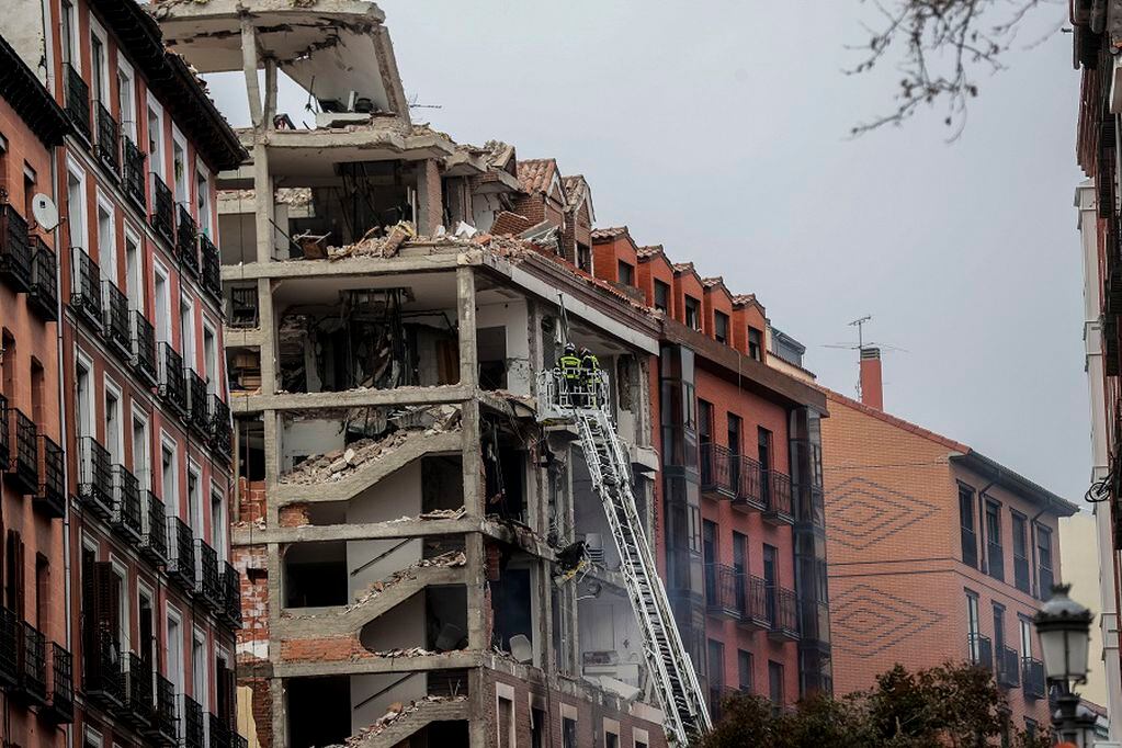 Firefighters work on a damaged building at Toledo Street following an explosion in downtown Madrid, Spain, Wednesday, Jan. 20, 2021. A loud explosion has partially destroyed a small building flanked by a school and a nursing home in the center of Spain's capital. (AP Photo/Paul White)
