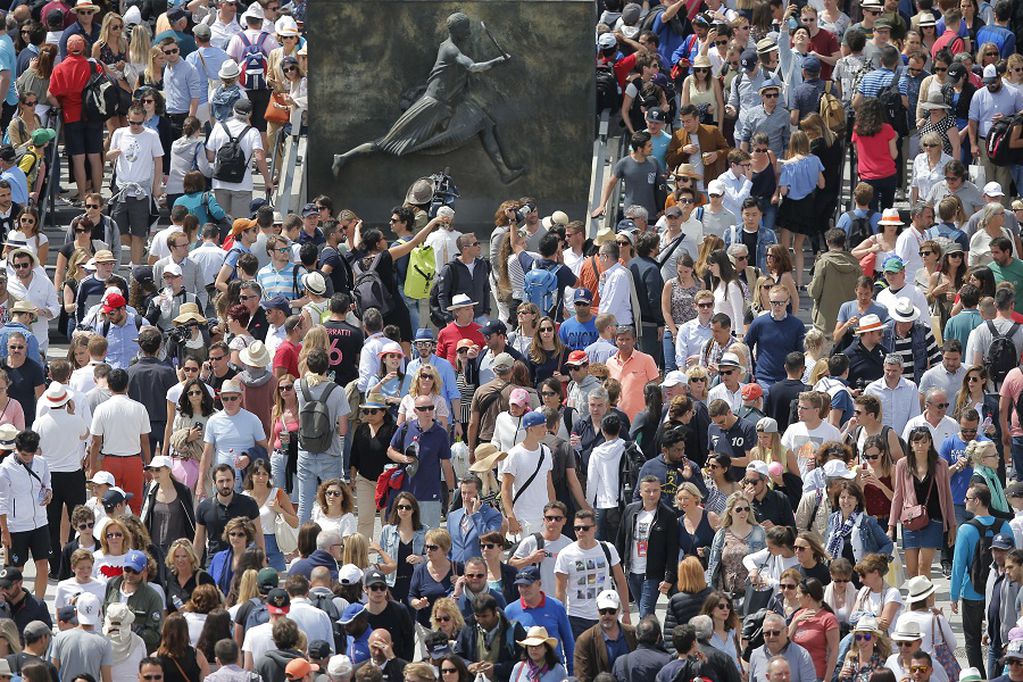 FILE - In this June 4, 2017 file photo, spectators crowd around a bronze plaque of French tennis player Suzanne Lenglen at the French Open tennis tournament at the Roland Garros stadium, in Paris. The French Tennis Federation says up to 60% of the stands can be filled with fans when play starts in September at Roland Garros. The clay-court tournament had been scheduled to start on May 24 but was postponed to Sept. 20 because of the coronavirus pandemic. (AP Photo/Michel Euler, File)