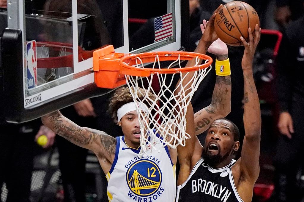Brooklyn Nets forward Kevin Durant (7) shoots as Golden State Warriors forward Kelly Oubre Jr., (12) defends during the first quarter of an opening night NBA basketball game, Tuesday, Dec. 22, 2020, in New York. (AP Photo/Kathy Willens)